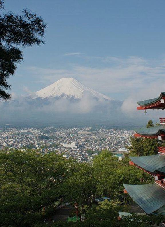 Mount Fuji rising beyond a red pagoda above a town
