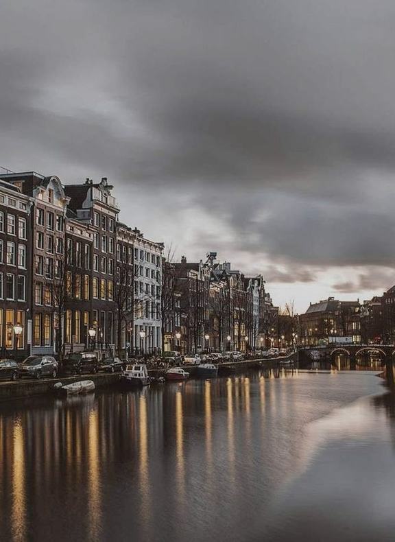 An Amsterdam canal lined with gabled houses at dusk