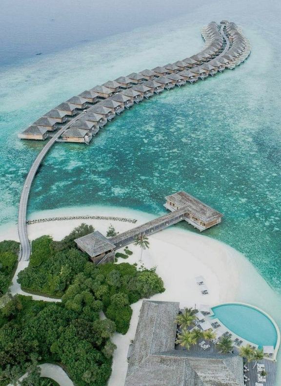 Overwater villas curving out across a turquoise lagoon