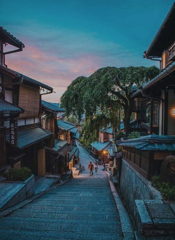 A stone lane of wooden machiya houses in Kyoto at dusk