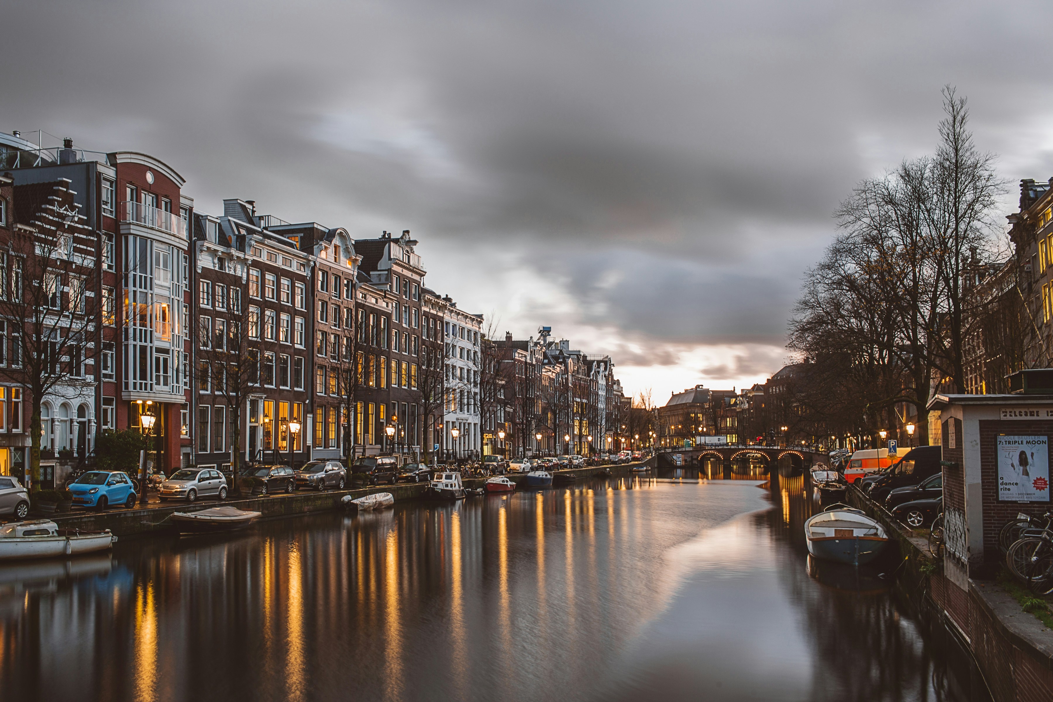 Amsterdam canal at dusk with gabled townhouses reflected in still water