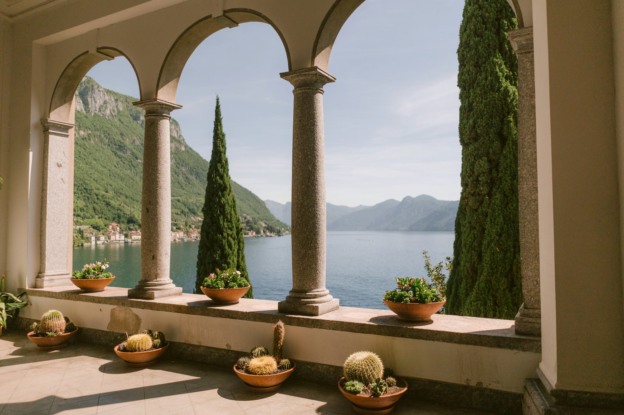 A view of Lake Como through the stone arches of a lakeside villa