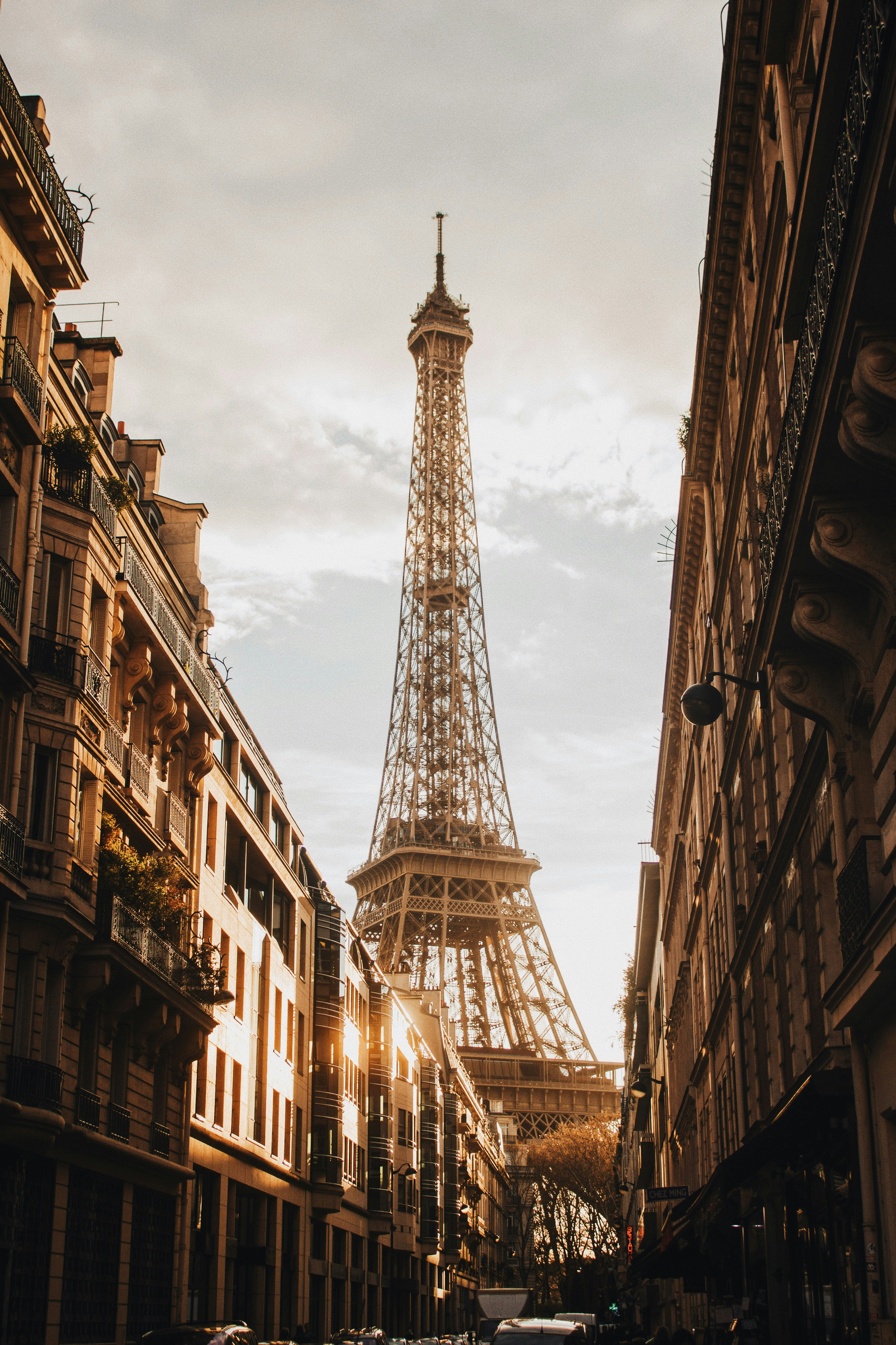The Eiffel Tower glowing at sunset seen from a Haussmann boulevard in Paris