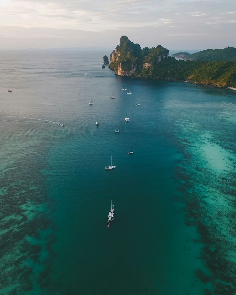 Sailboats anchored off limestone cliffs in the Andaman Sea
